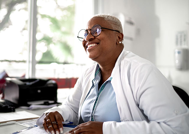 Doctor smiling at desk doing paperwork
