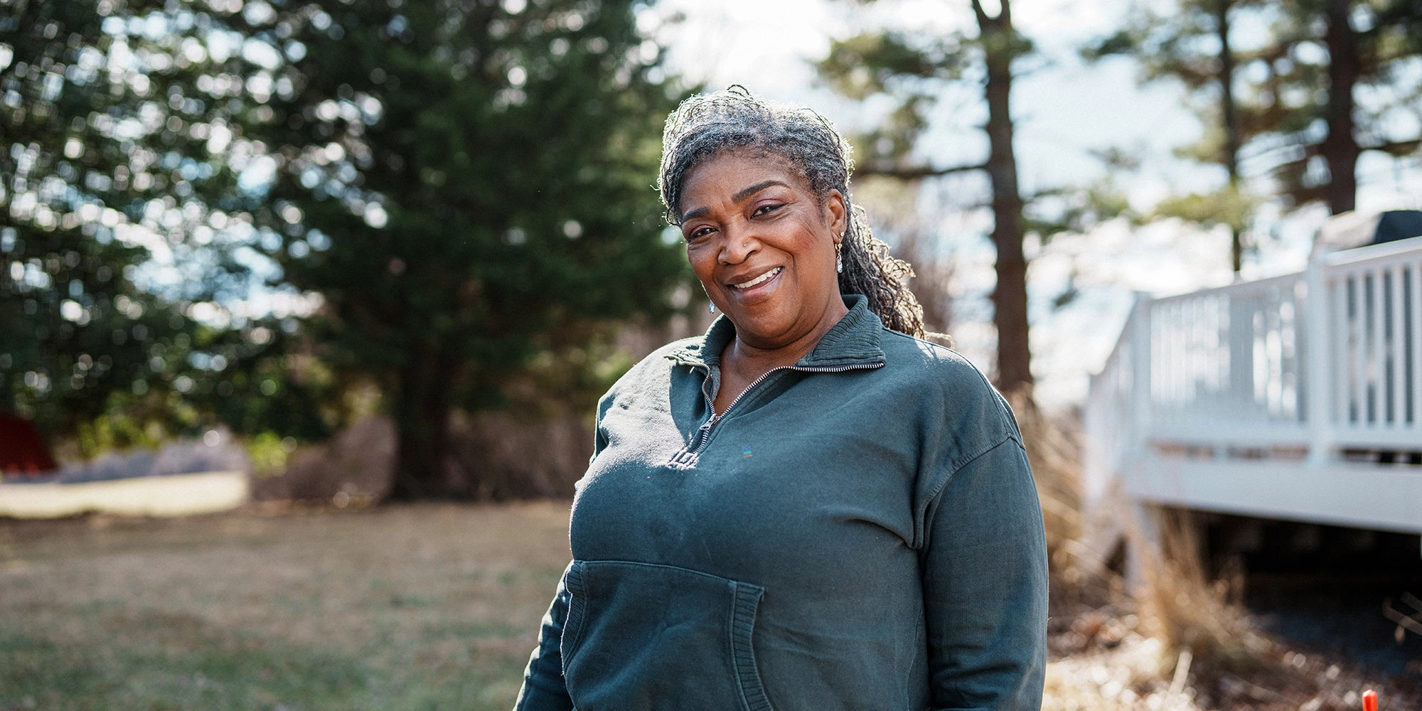 A woman stands by a backyard deck on a chilly fall day