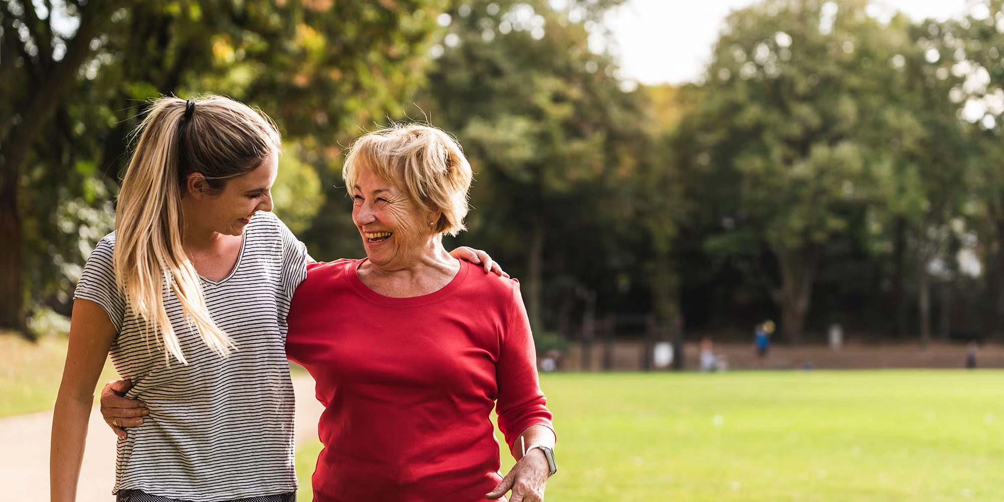 An older daughter and her mother wander through a park together