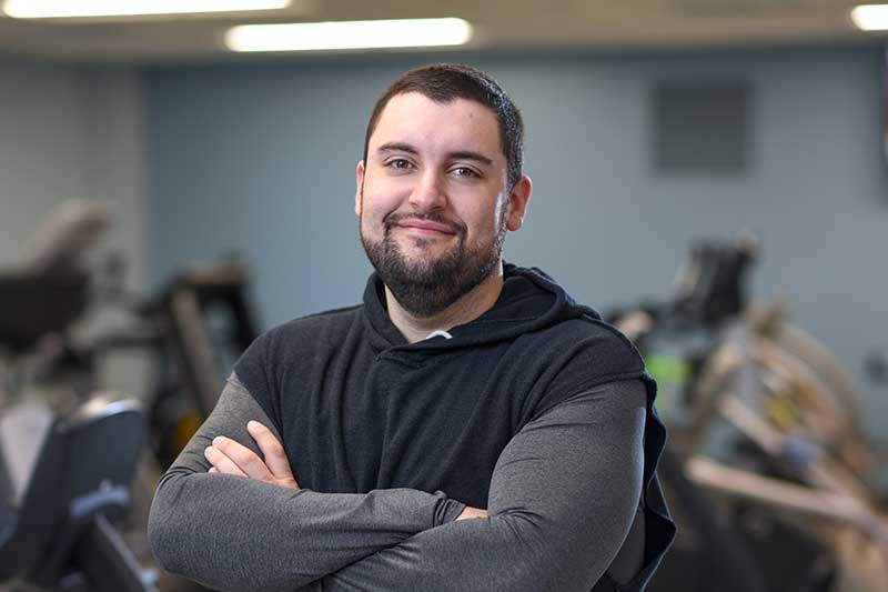 Michael Davis stands with his arms crossed, smiling while in an exercise room