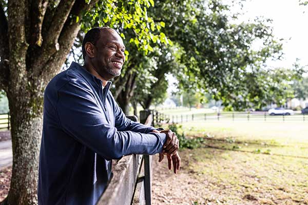 A man leans against a fence overlooking a field